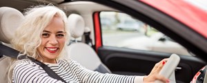 Smiling woman sitting in driver's seat in her car