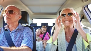 Senior couple in car with granchildren