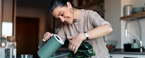Mature woman watering houseplant