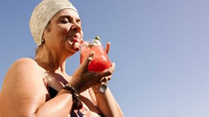 Older woman in swimming hat drinking through a straw