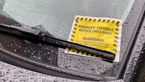 Yellow parking ticket on car windshield