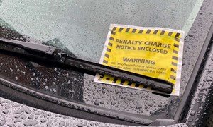 Yellow parking ticket on car windshield