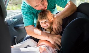 Little girl being buckled into car seat