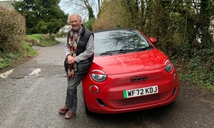 Older man next to his red electric car