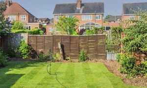 Garden with wooden fence panel at back and overlooking houses