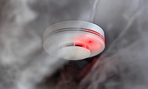 Close up of home fire alarm surrounded by smoke