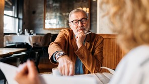 Professional man seated at table and talking to client 