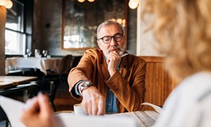 Professional man seated at table and talking to client 