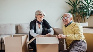 Couple laughing at home surrounded by packing boxes