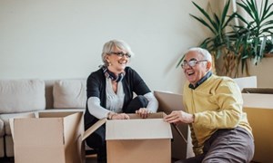 Couple laughing at home surrounded by packing boxes