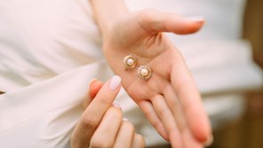 A woman looks at a pair of earrings.