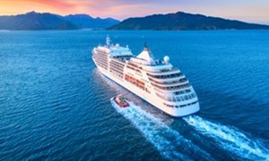 Cruise ship at sea heading to land at sunset