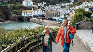 Couple walking along with a picturesque village behind them