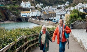 Couple walking along with a picturesque village behind them