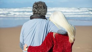 A older couple hug each other on a beach