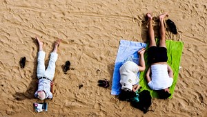 Three people laying on the sand